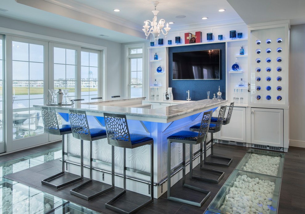 Mid-sized beach style u-shaped seated home bar in Philadelphia with an undermount sink, shaker cabinets, white cabinets, marble benchtops, blue splashback, dark hardwood floors, brown floor and grey benchtop.