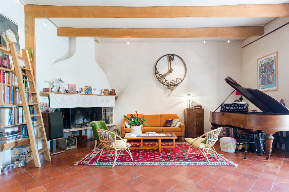 Photo of an eclectic formal living room in Montpellier with white walls, terra-cotta floors, a corner fireplace, no tv and red floor.