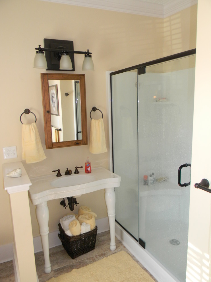 Mid-sized traditional 3/4 bathroom in Raleigh with an alcove shower, yellow walls, ceramic floors, a wall-mount sink, brown floor and a hinged shower door.