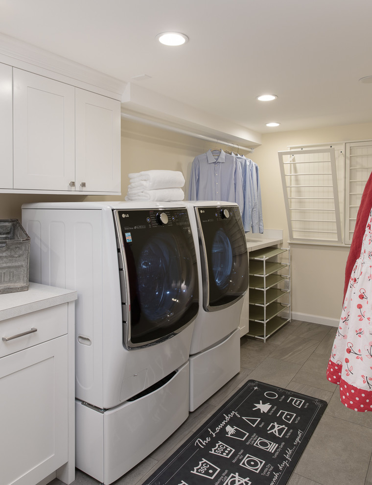 Design ideas for a large modern galley dedicated laundry room in Seattle with a drop-in sink, shaker cabinets, white cabinets, laminate benchtops, yellow walls, porcelain floors, a side-by-side washer and dryer and grey floor.