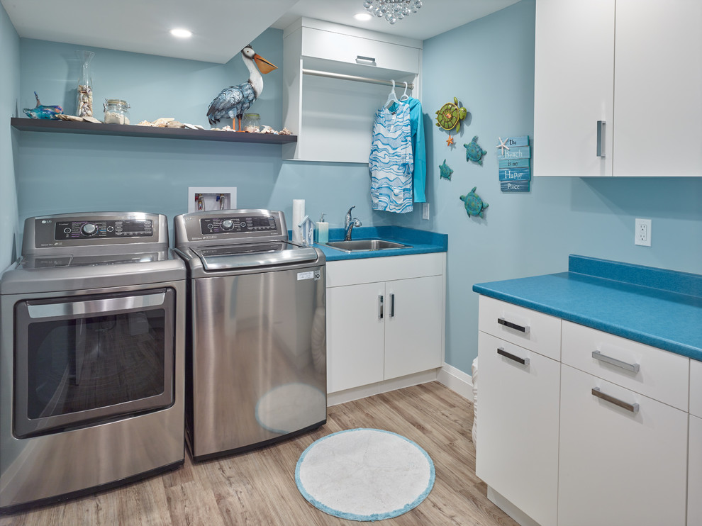 Mid-sized transitional l-shaped dedicated laundry room in Vancouver with a drop-in sink, flat-panel cabinets, white cabinets, laminate benchtops, blue walls, medium hardwood floors, a side-by-side washer and dryer, brown floor and blue benchtop.