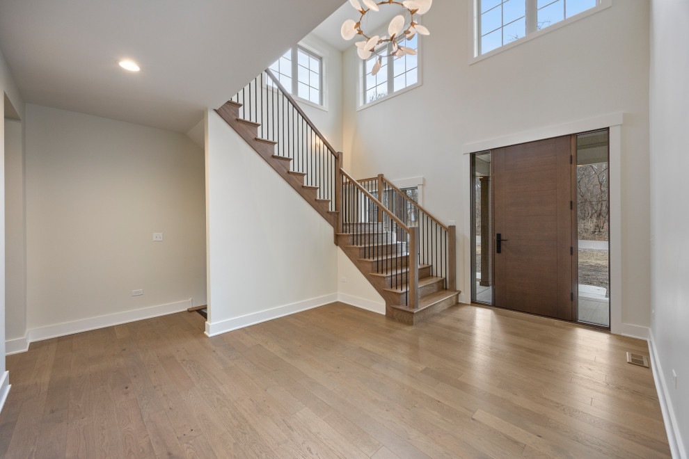 Inspiration for a large transitional light wood floor, brown floor and vaulted ceiling foyer remodel in Chicago with white walls and a dark wood front door