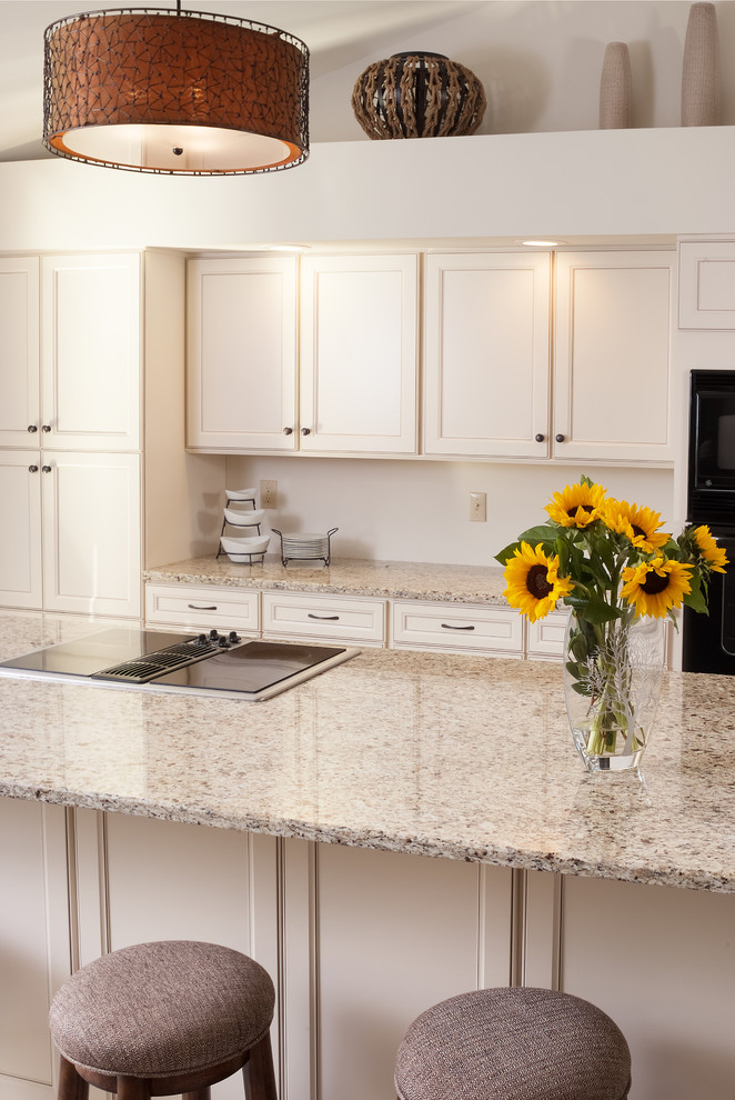 Inspiration for a mid-sized rustic galley porcelain tile and beige floor open concept kitchen remodel with an undermount sink, recessed-panel cabinets, white cabinets, quartz countertops, black appliances, an island and beige countertops