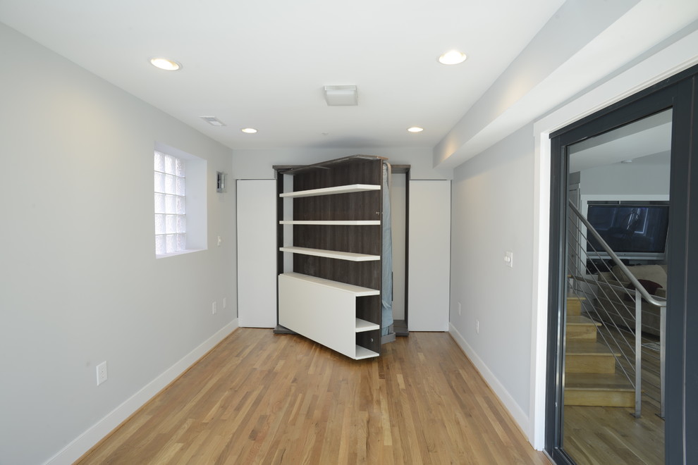 This is an example of a small modern guest bedroom in DC Metro with white walls, light hardwood floors and no fireplace.