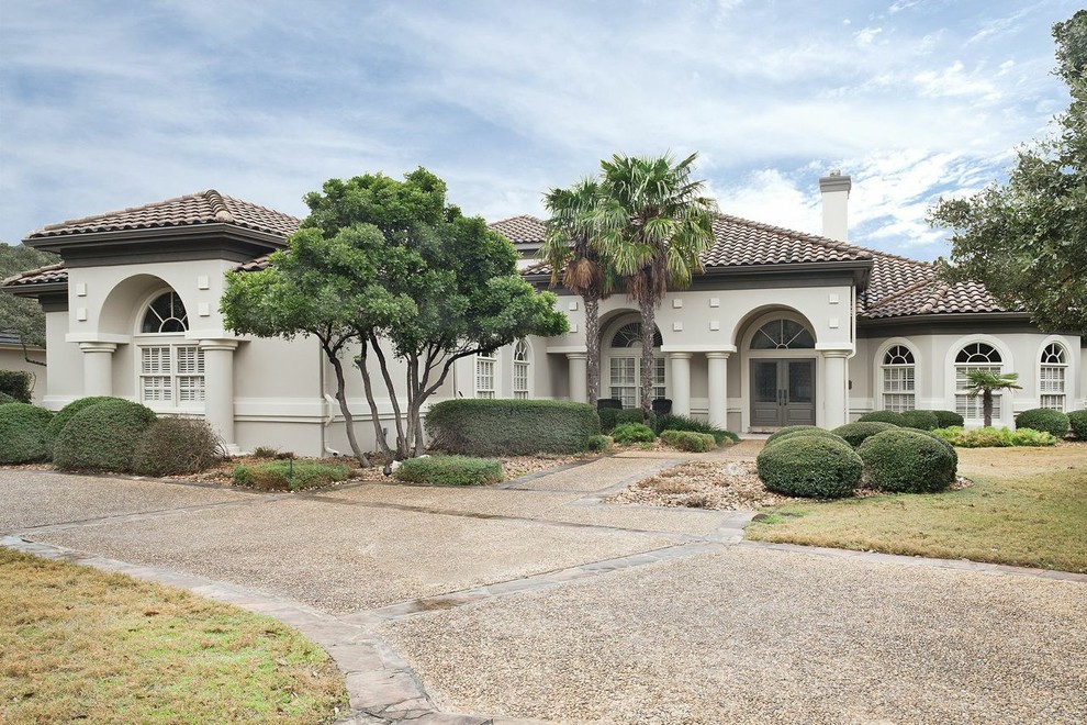 This is an example of an expansive transitional two-storey stucco beige house exterior in Austin with a gable roof and a shingle roof.