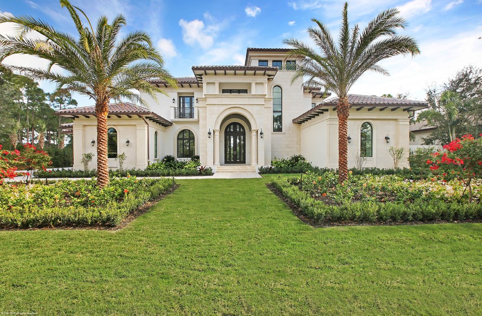 This is an example of an expansive mediterranean two-storey beige exterior in Miami with mixed siding.