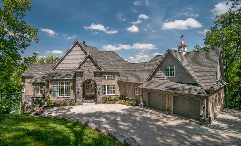 Photo of an expansive eclectic two-storey beige exterior in Charlotte with stone veneer and a hip roof.