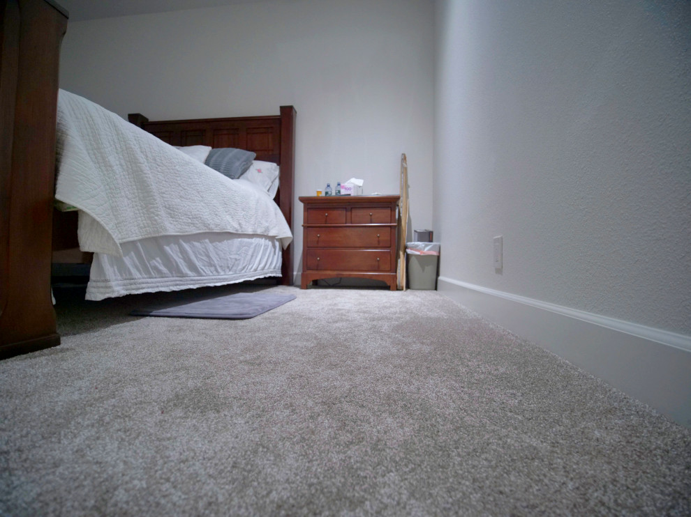Großes Modernes Hauptschlafzimmer mit weißer Wandfarbe, Teppichboden, grauem Boden, Eckkamin und Kaminumrandung aus Stein in Sacramento