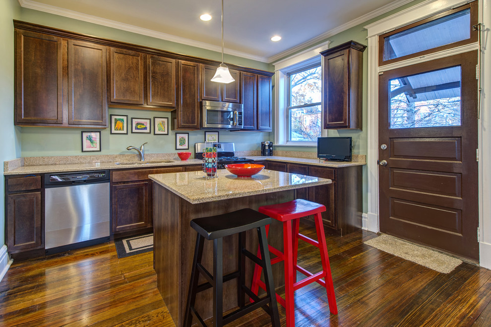 Mid-sized traditional l-shaped kitchen in St Louis with stainless steel appliances, recessed-panel cabinets, dark wood cabinets, a double-bowl sink, dark hardwood floors, with island and brown floor.