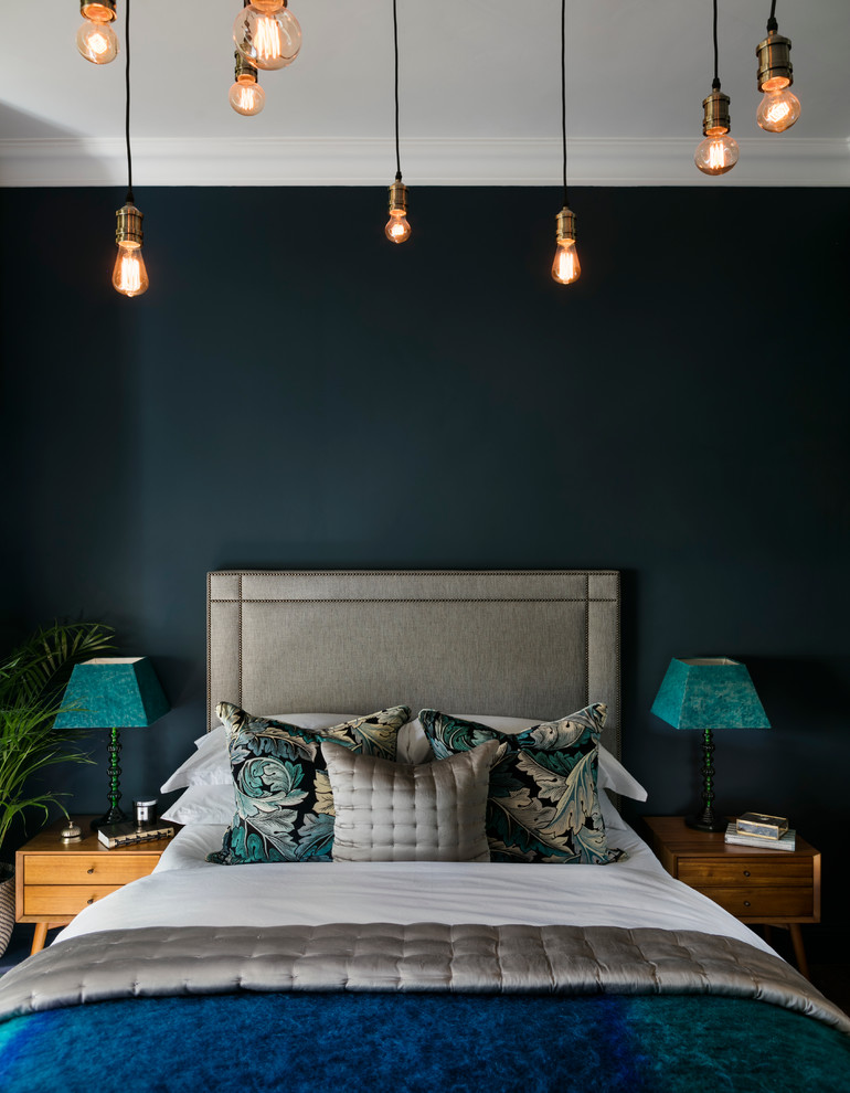 This is an example of an eclectic master bedroom in London with blue walls and dark hardwood floors.