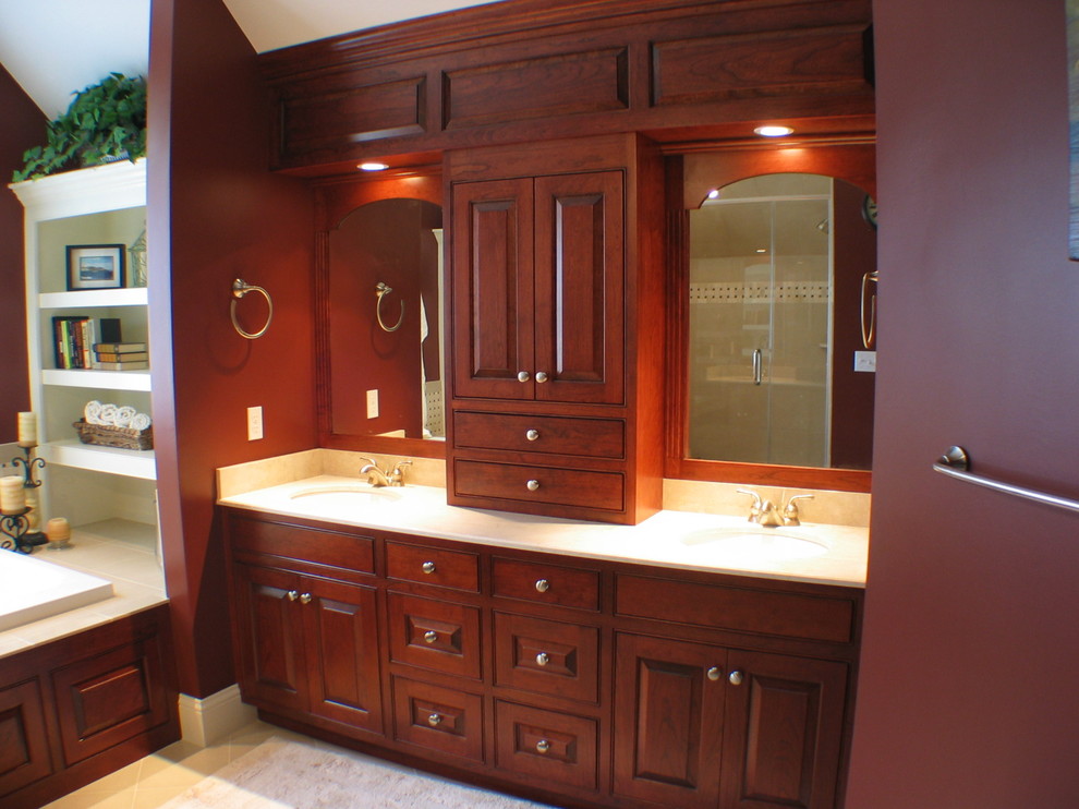 Photo of an expansive traditional master bathroom in Boston with raised-panel cabinets, orange walls, marble floors, an undermount sink, marble benchtops, medium wood cabinets, a drop-in tub, beige floor and white benchtops.