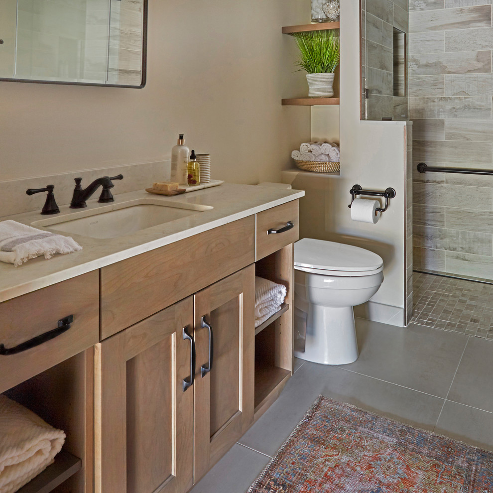 This is an example of a small arts and crafts 3/4 bathroom in Chicago with shaker cabinets, light wood cabinets, an alcove shower, a two-piece toilet, multi-coloured tile, porcelain tile, beige walls, porcelain floors, an undermount sink, engineered quartz benchtops, grey floor, a hinged shower door and grey benchtops.