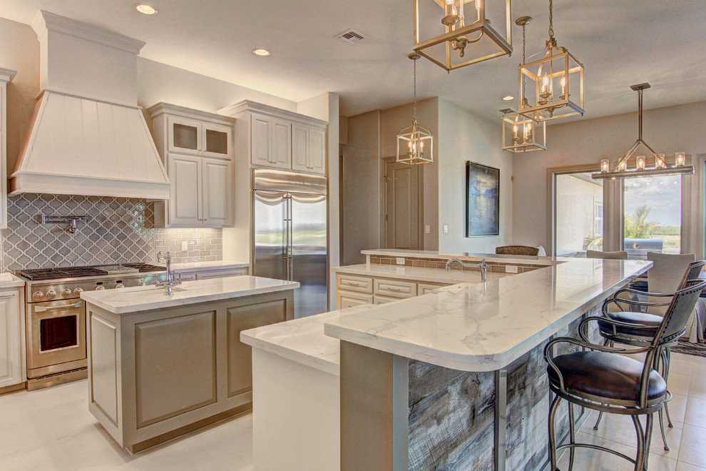 Example of a transitional u-shaped beige floor eat-in kitchen design with an undermount sink, raised-panel cabinets, beige cabinets, gray backsplash, ceramic backsplash, stainless steel appliances and an island