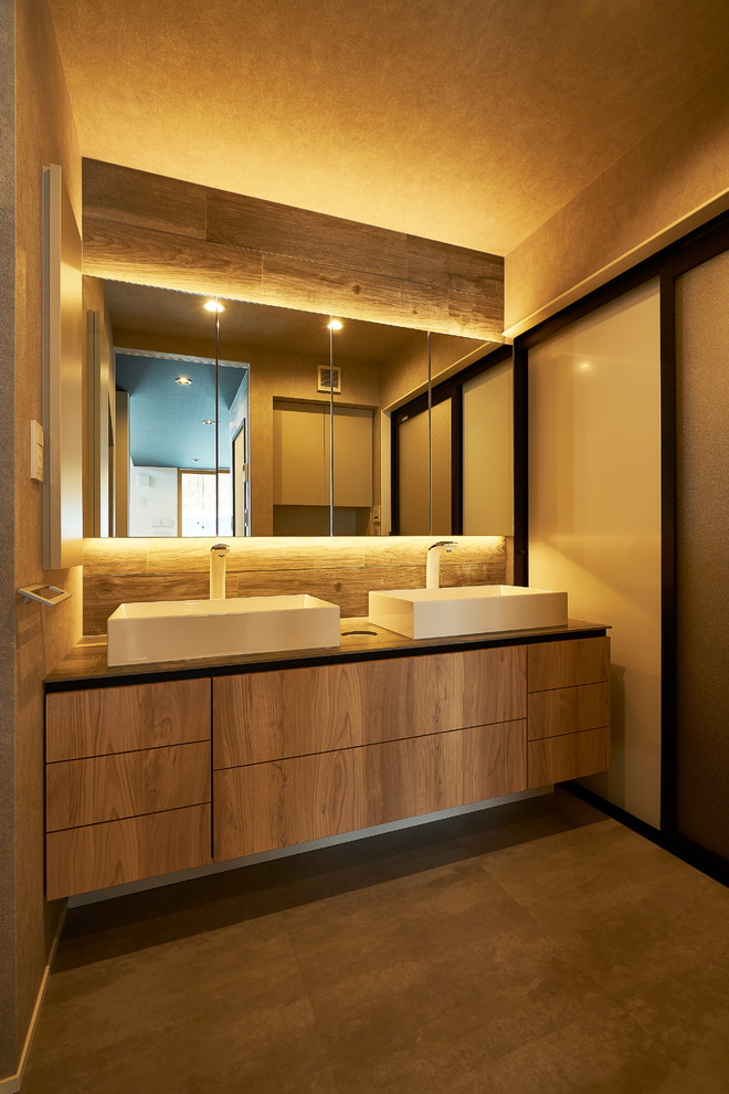 This is an example of a modern powder room in Other with flat-panel cabinets, medium wood cabinets, brown walls, a vessel sink, wood benchtops, brown floor and brown benchtops.