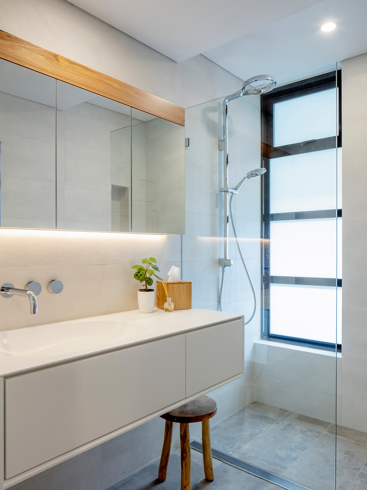 Photo of a contemporary bathroom in Sydney with flat-panel cabinets, white cabinets, a curbless shower, white tile, white walls, an integrated sink, grey floor, an open shower and white benchtops.