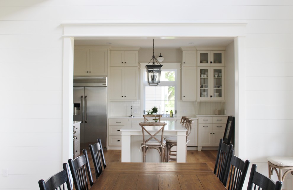 Large transitional l-shaped eat-in kitchen photo in Toronto with an undermount sink, shaker cabinets, white cabinets, quartz countertops, white backsplash, stainless steel appliances and an island