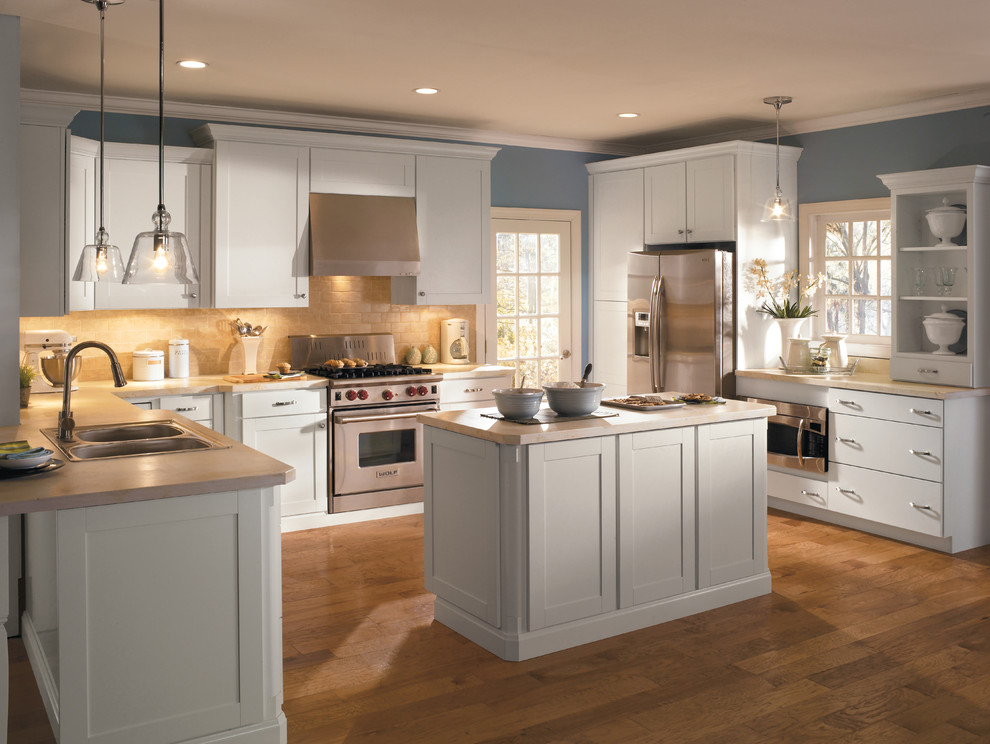 Inspiration for a mid-sized traditional u-shaped eat-in kitchen in Indianapolis with an undermount sink, shaker cabinets, white cabinets, laminate benchtops, beige splashback, ceramic splashback, stainless steel appliances, light hardwood floors and with island.