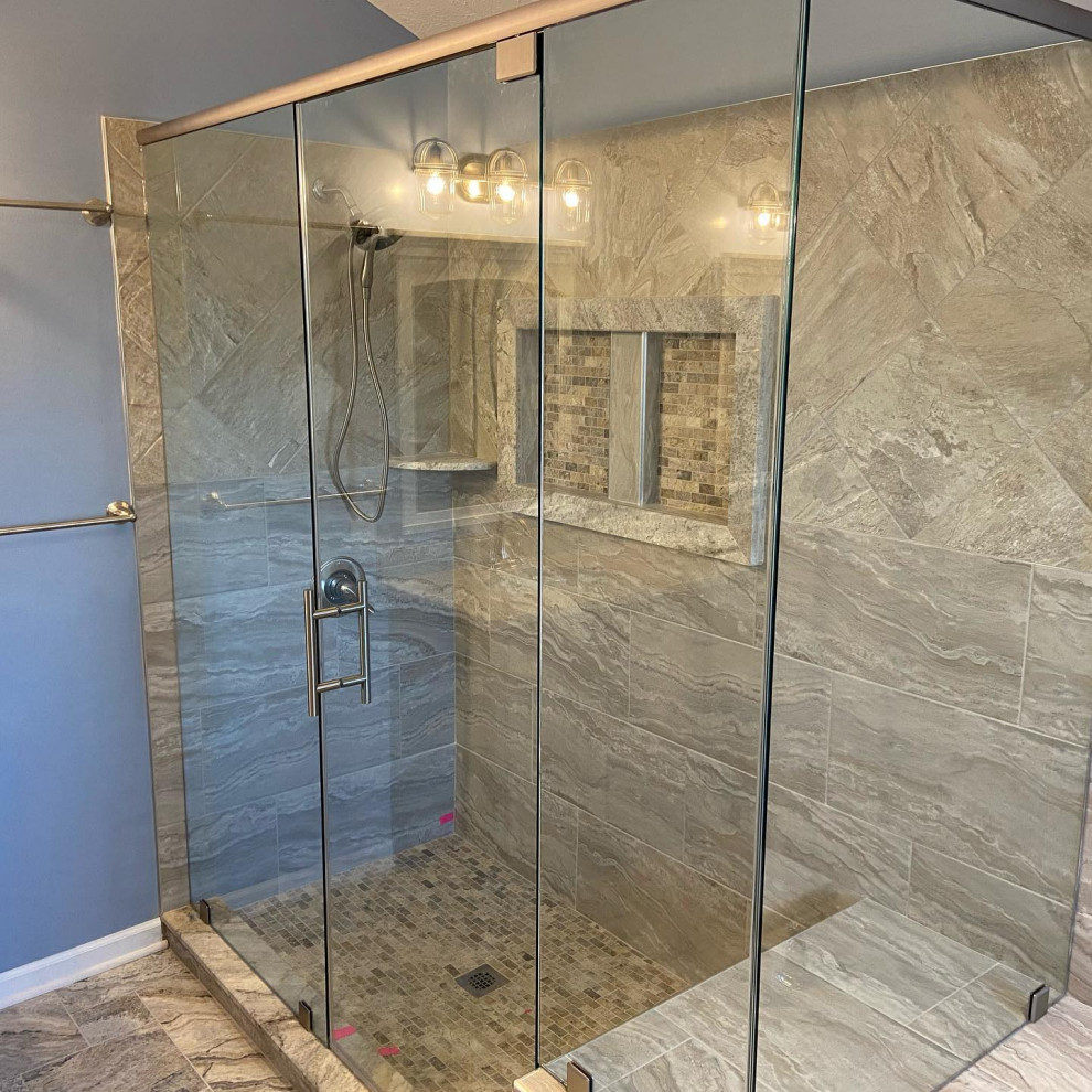 Photo of a large modern master bathroom in Indianapolis with raised-panel cabinets, grey cabinets, a drop-in tub, a corner shower, a one-piece toilet, multi-coloured tile, stone tile, blue walls, travertine floors, an undermount sink, granite benchtops, multi-coloured floor, a hinged shower door and beige benchtops.