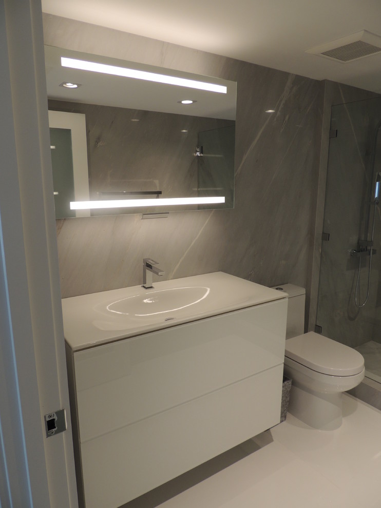 Mid-sized contemporary 3/4 bathroom in Miami with white cabinets, quartzite benchtops, porcelain tile, a wall-mount sink, flat-panel cabinets, an alcove shower, a one-piece toilet, white tile, grey walls and porcelain floors.
