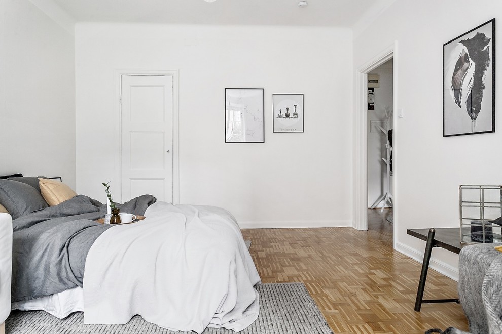 Example of a danish medium tone wood floor and brown floor bedroom design in Stockholm with white walls