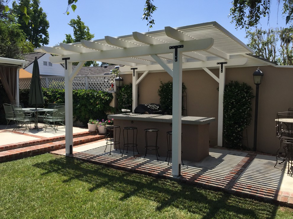 Mid-sized elegant backyard concrete patio kitchen photo in Los Angeles with a pergola
