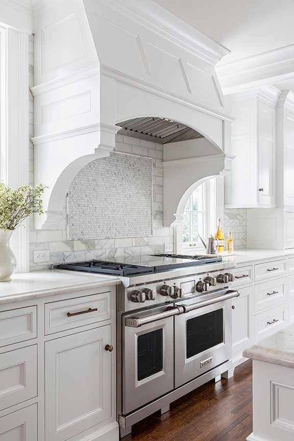 Design ideas for a large traditional l-shaped open plan kitchen in Minneapolis with a single-bowl sink, recessed-panel cabinets, white cabinets, quartzite benchtops, white splashback, stone tile splashback, panelled appliances, dark hardwood floors and with island.