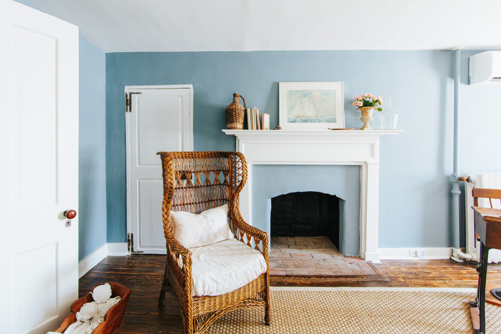 Foto de dormitorio principal clásico grande con paredes azules, suelo de madera en tonos medios, todas las chimeneas, marco de chimenea de yeso, suelo marrón y vigas vistas