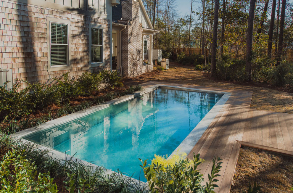Cette photo montre une grande piscine arrière craftsman rectangle avec une terrasse en bois.