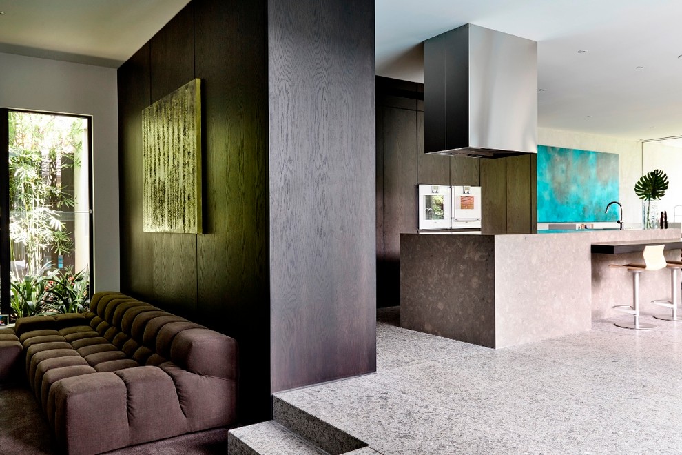 This is an example of a contemporary l-shaped kitchen in Melbourne with dark wood cabinets, white appliances, limestone floors and with island.