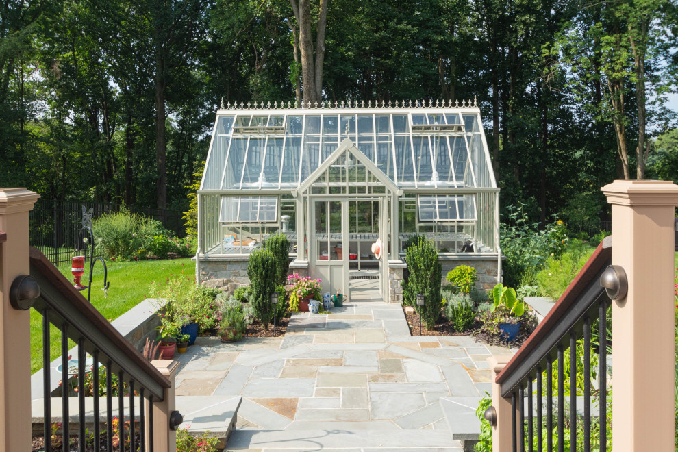 Foto di un grande giardino formale tradizionale esposto in pieno sole dietro casa in primavera con un ingresso o sentiero, pavimentazioni in pietra naturale e recinzione in metallo