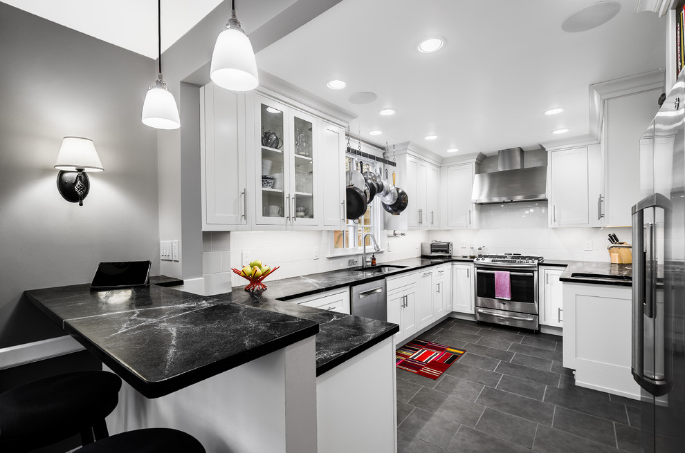 Small modern u-shaped eat-in kitchen in Philadelphia with an undermount sink, beaded inset cabinets, white cabinets, soapstone benchtops, white splashback, stainless steel appliances, porcelain floors, a peninsula and glass sheet splashback.