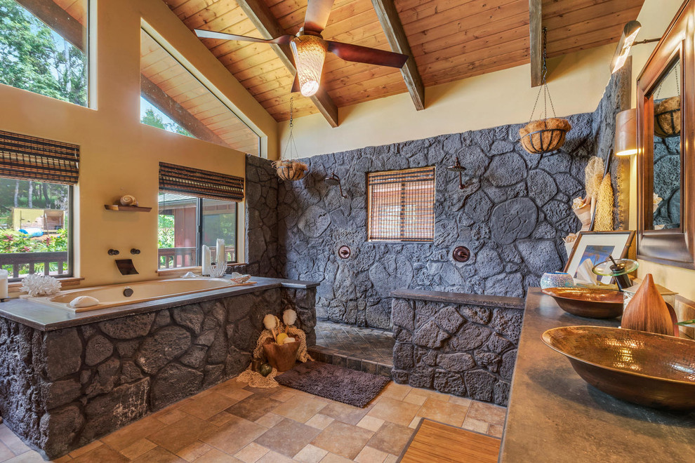 This is an example of a tropical master bathroom in Hawaii with a drop-in tub, a double shower, stone tile, beige walls, a vessel sink and an open shower.