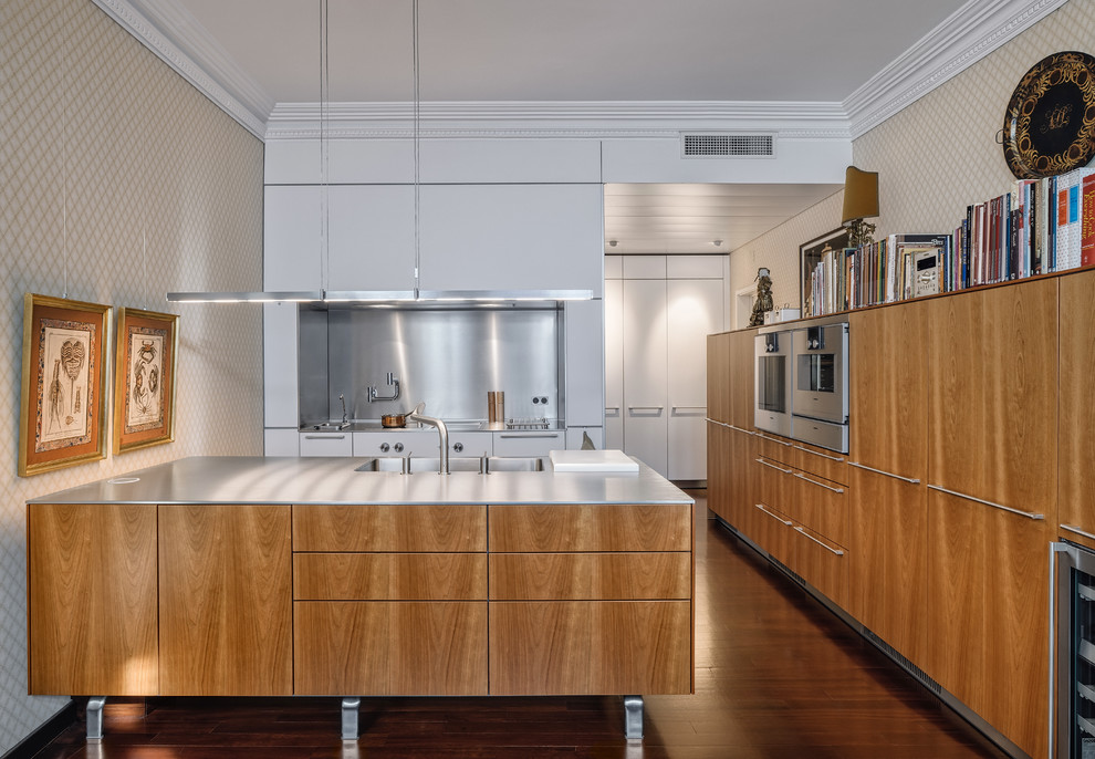 Photo of a mid-sized transitional galley open plan kitchen in Barcelona with a single-bowl sink, flat-panel cabinets, medium wood cabinets, stainless steel benchtops, metallic splashback, medium hardwood floors and a peninsula.