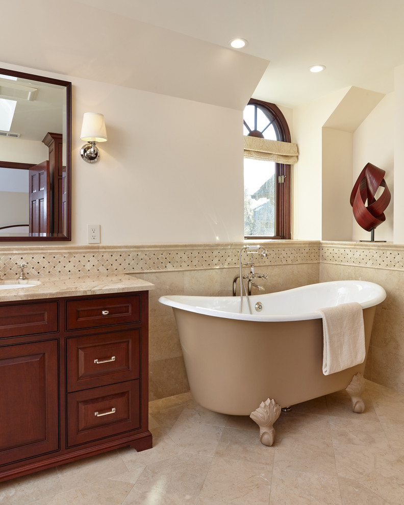 Inspiration for a large traditional master bathroom in San Francisco with a claw-foot tub, an undermount sink, dark wood cabinets, beige tile, beige walls, beige floor, beaded inset cabinets and marble floors.