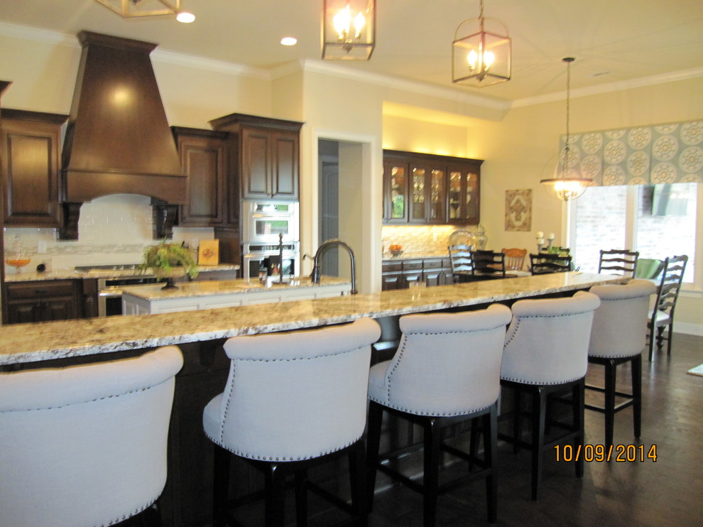 Inspiration for a large transitional galley dark wood floor eat-in kitchen remodel with an undermount sink, raised-panel cabinets, dark wood cabinets, granite countertops, multicolored backsplash, ceramic backsplash, stainless steel appliances and an island