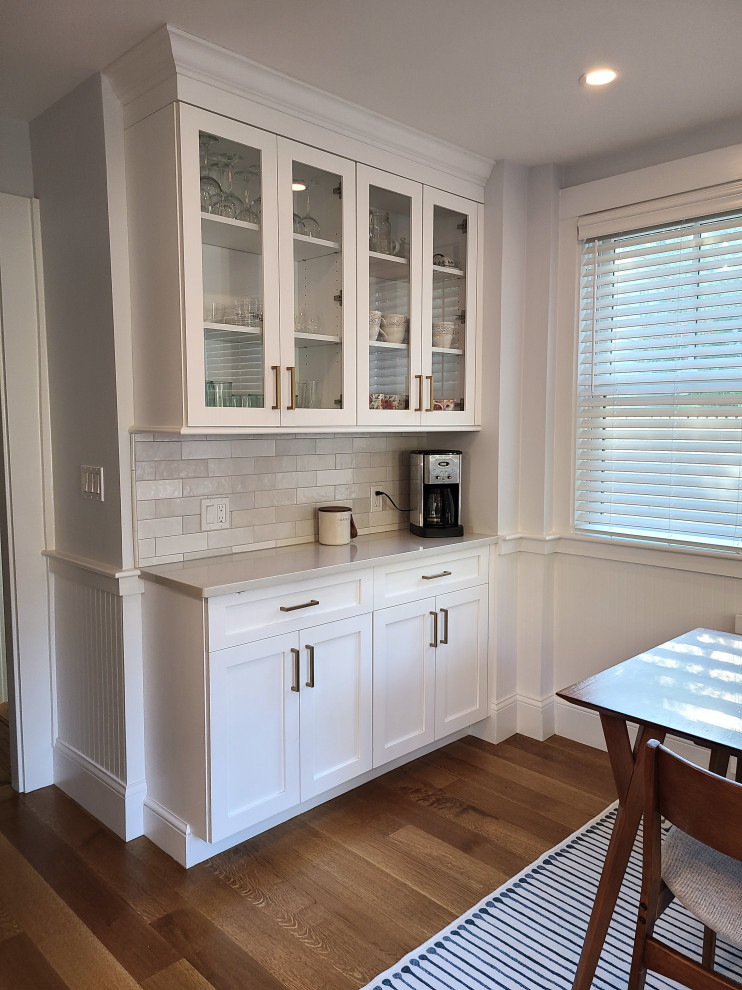 Inspiration for a large transitional u-shaped medium tone wood floor and brown floor eat-in kitchen remodel in Boston with recessed-panel cabinets, white cabinets, an island, white countertops, white backsplash and subway tile backsplash