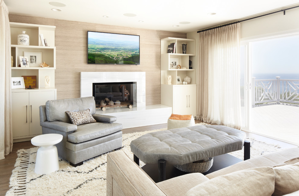 Inspiration for a beach style living room in Los Angeles with beige walls, a standard fireplace, a wall-mounted tv and dark hardwood floors.