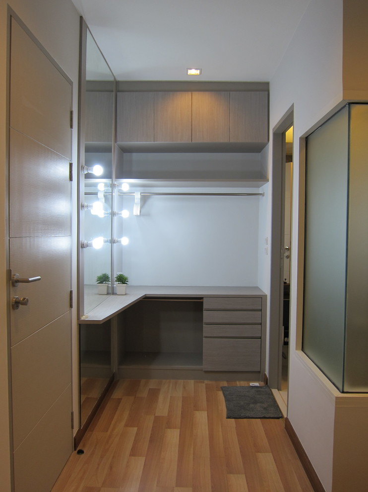 Mid-sized modern gender-neutral dressing room in New York with flat-panel cabinets, grey cabinets and light hardwood floors.