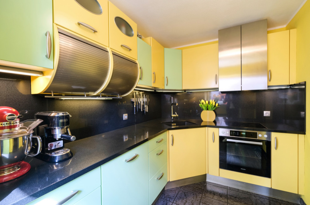 ミュンヘンにあるお手頃価格の広いトラディショナルスタイルのおしゃれなキッチン (アンダーカウンターシンク、黄色いキャビネット、クオーツストーンカウンター、黒いキッチンパネル、クオーツストーンのキッチンパネル、シルバーの調理設備、黒いキッチンカウンター) の写真