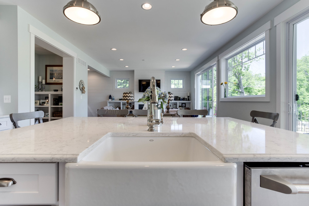 Inspiration for a large beach style kitchen in Baltimore with a farmhouse sink, recessed-panel cabinets, white cabinets, quartz benchtops, stainless steel appliances, light hardwood floors and with island.