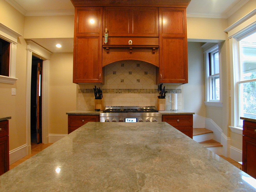 Inspiration for a mid-sized transitional galley light wood floor eat-in kitchen remodel in Boston with an undermount sink, recessed-panel cabinets, dark wood cabinets, granite countertops, beige backsplash, stone tile backsplash, stainless steel appliances and an island