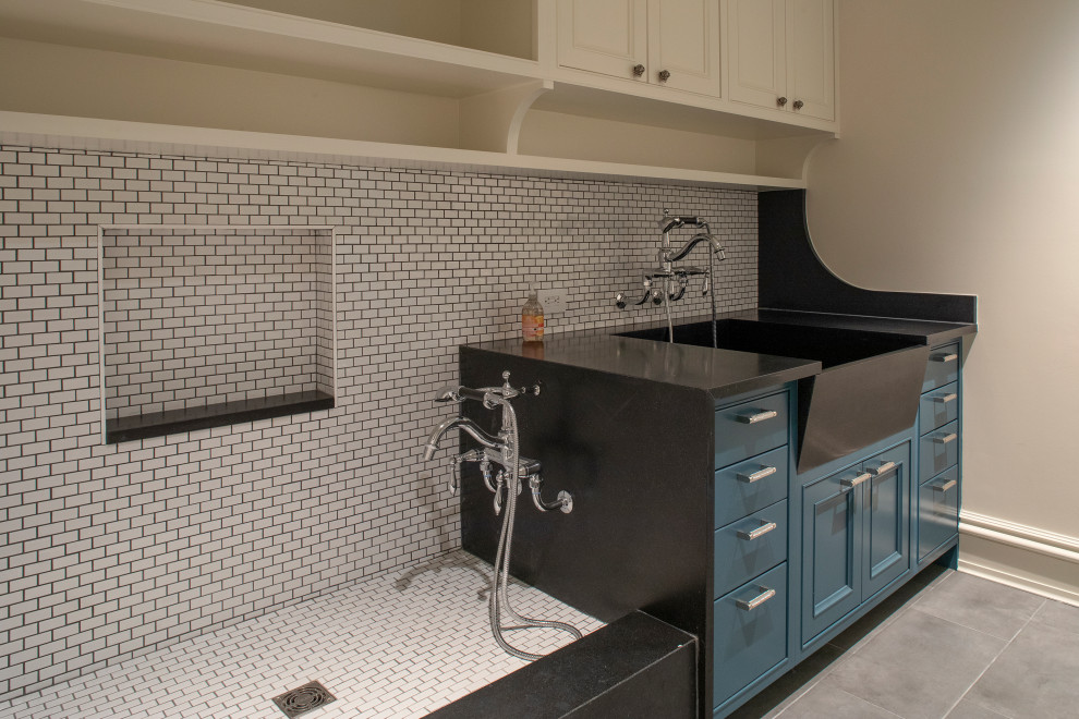 This is an example of a large nautical galley laundry cupboard in Other with a belfast sink, recessed-panel cabinets, blue cabinets, white splashback, ceramic splashback, white walls, ceramic flooring, a side by side washer and dryer, grey floors and grey worktops.