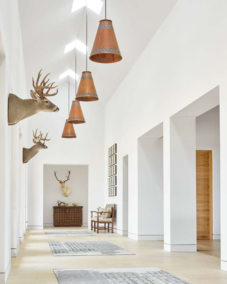 Entry hall - large rustic ceramic tile, beige floor and vaulted ceiling entry hall idea in Austin with white walls and a medium wood front door
