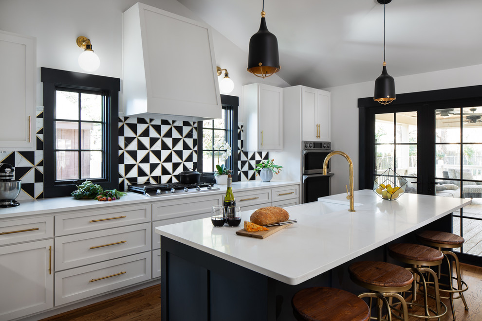 Small transitional u-shaped open plan kitchen in Birmingham with recessed-panel cabinets, white cabinets, quartzite benchtops, black splashback, ceramic splashback, stainless steel appliances, medium hardwood floors, with island, brown floor, white benchtop and a farmhouse sink.