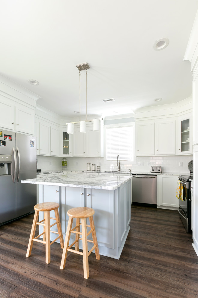 Inspiration for a country u-shaped eat-in kitchen in Charleston with shaker cabinets, white cabinets, white splashback, stainless steel appliances, dark hardwood floors, with island, brown floor, grey benchtop and an undermount sink.