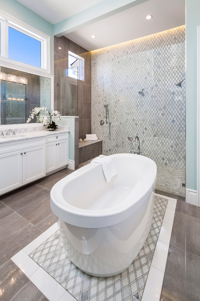 Photo of a large transitional master bathroom in Miami with flat-panel cabinets, white cabinets, an open shower, multi-coloured tile, mosaic tile, blue walls, a drop-in sink and a freestanding tub.