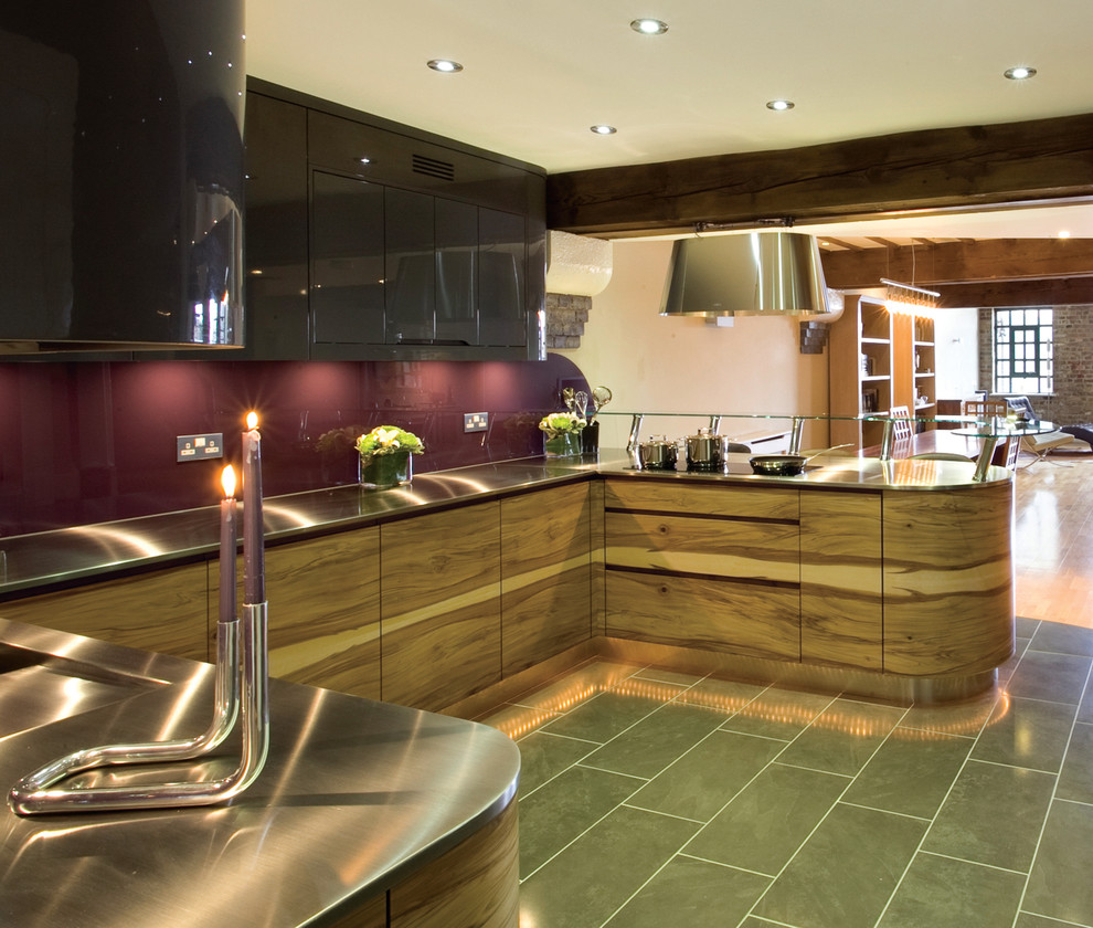 Example of a mid-sized eclectic u-shaped ceramic tile open concept kitchen design in London with an undermount sink, flat-panel cabinets, medium tone wood cabinets, stainless steel countertops, pink backsplash, glass sheet backsplash, stainless steel appliances and an island