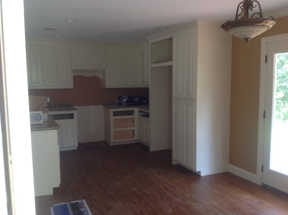 Example of a small mountain style l-shaped light wood floor eat-in kitchen design with a double-bowl sink, raised-panel cabinets, white cabinets, granite countertops, stainless steel appliances and an island