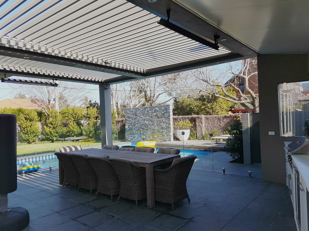 Design ideas for a large contemporary backyard patio in Melbourne with an outdoor kitchen, natural stone pavers and a roof extension.