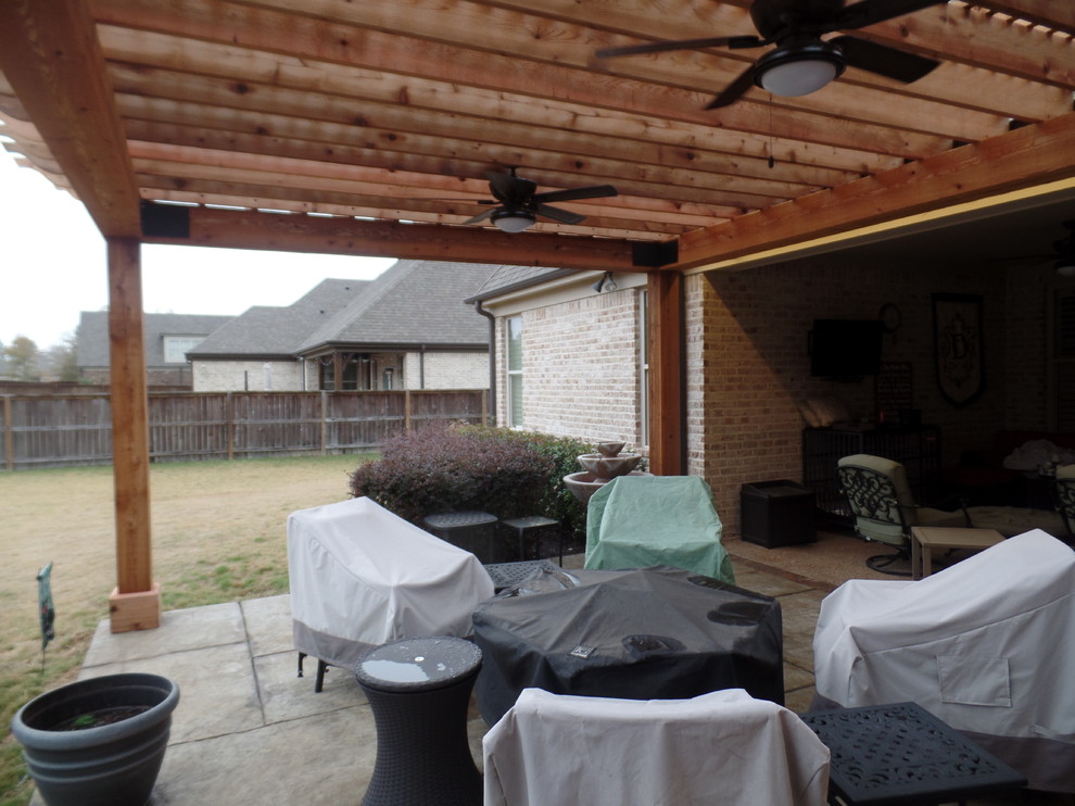 This is an example of a large country backyard patio in Other with stamped concrete and a pergola.